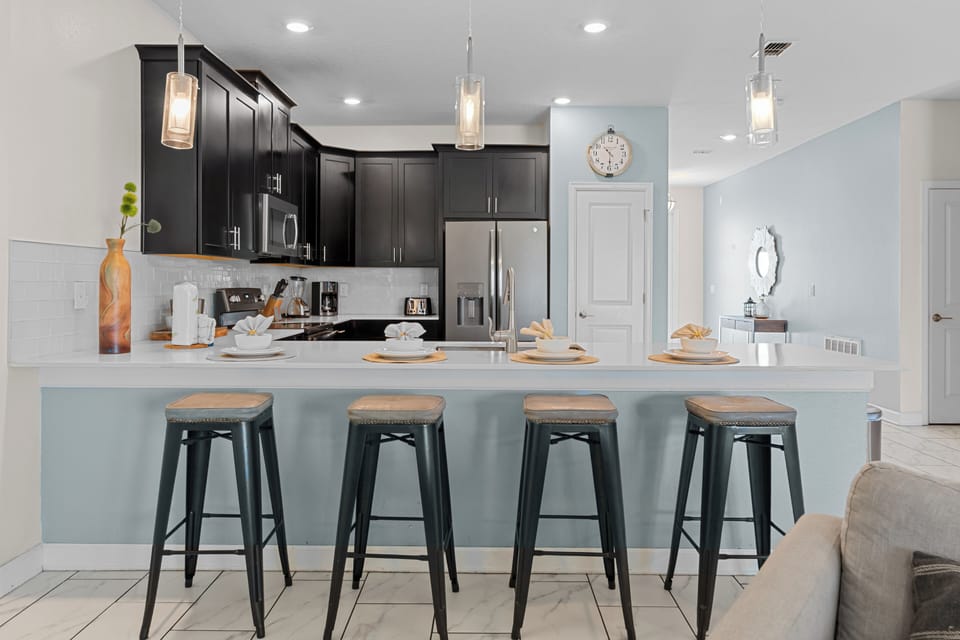 Your modern kitchen awaits with sleek dark cabinets, stainless appliances, and a spacious island perfect for morning coffee or evening meals together.