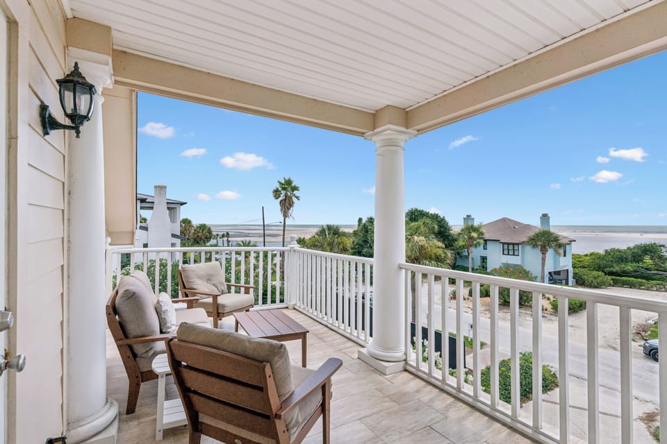 Relax on your private balcony with cozy seating and sweeping water views. The covered space offers shade while you soak in coastal breezes and palm-dotted scenery.