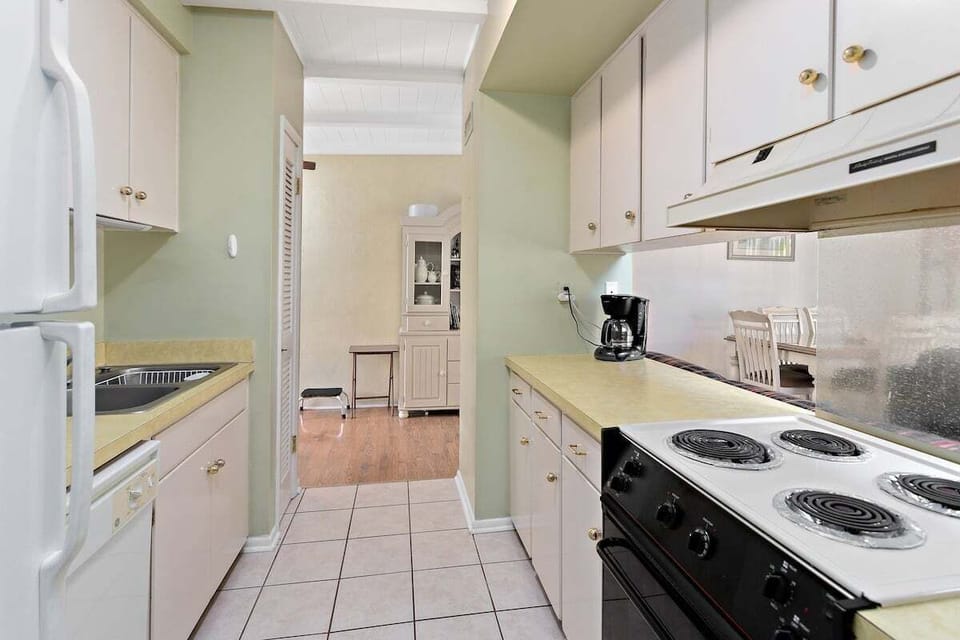 Side view of galley kitchen with white cabinets and appliances