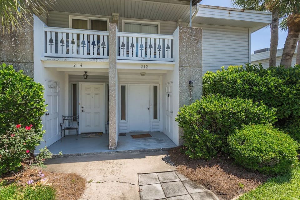 Property entrance with upper balcony and landscaped walkway