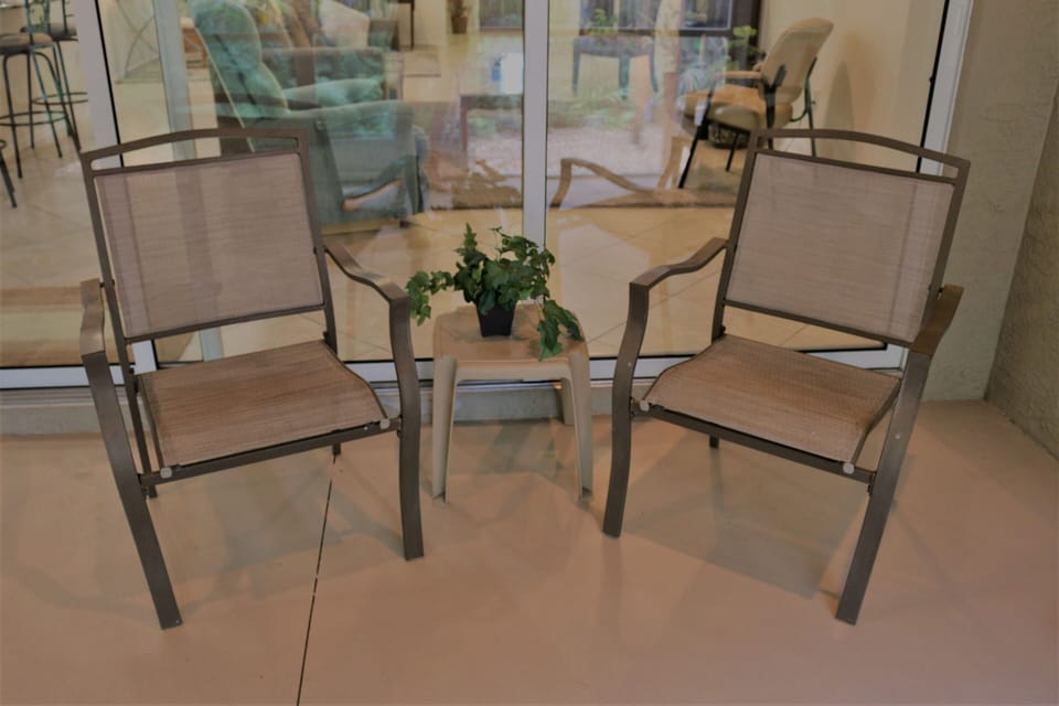Screened patio with table and four chairs overlooking lush greenery