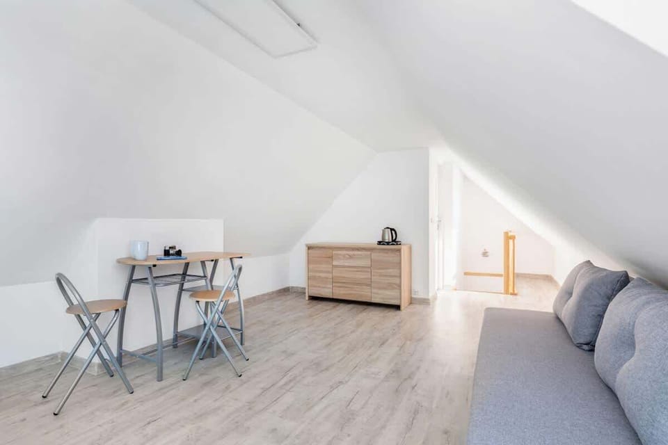 A modern living room with a gray sofa, a small wooden coffee table, and a minimalist white design.
