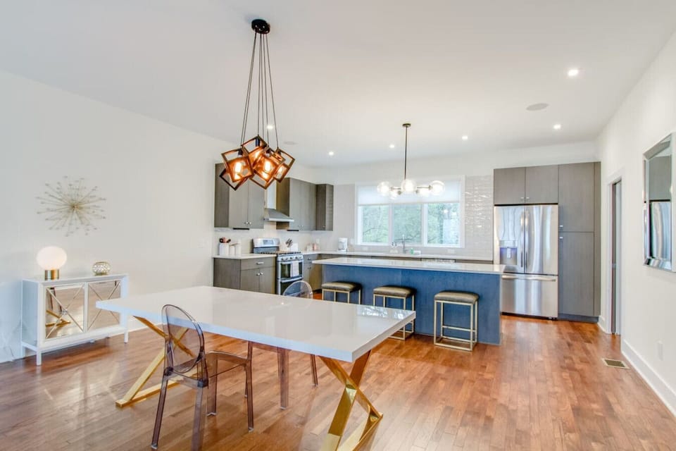 Kitchen from alternate angle showing dining area with chandelier and gray cabinets