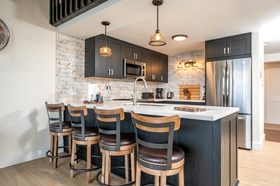 Gather around the spacious island with rich wood stools, textured stone walls, and warm loft-style ambiance    