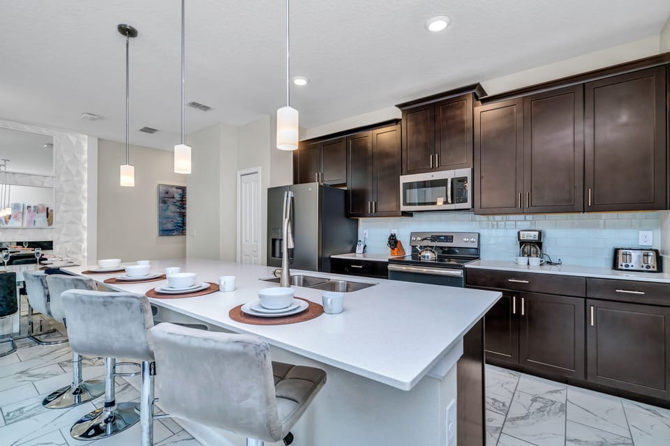 Sleek kitchen of the Townhouse in Kissimmee Florida - Sleek, stainless steel appliances - High Chair and Breakfast bar - Elegant and coordinated color palette for a cohesive look