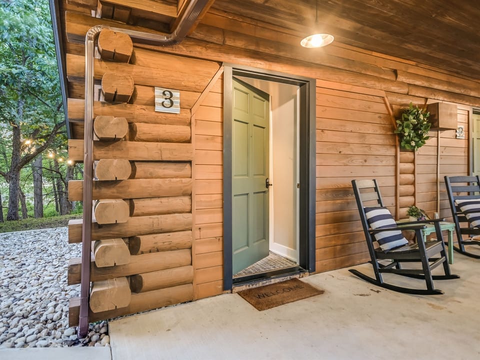  Private entrance to the Nature Suite at Cabins on the Square — cabin #3 with a covered porch, rocking chair, and smart-lock self check-in.