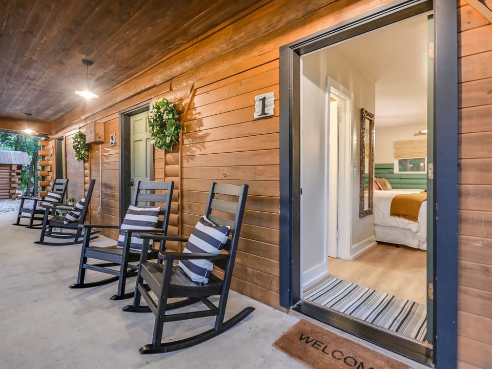 Covered porch with rocking chairs at the Sunshine Suite — your private entrance with smart-lock self check-in at Cabins on the Square.
