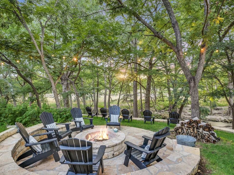Creekside fire pit at Cabins on the Square, surrounded by oak trees near downtown Wimberley