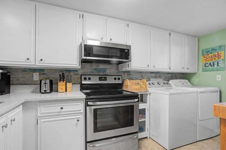 Fully equipped kitchen with modern appliances and crisp white cabinets offer a comfortable home-away-from-home experience.