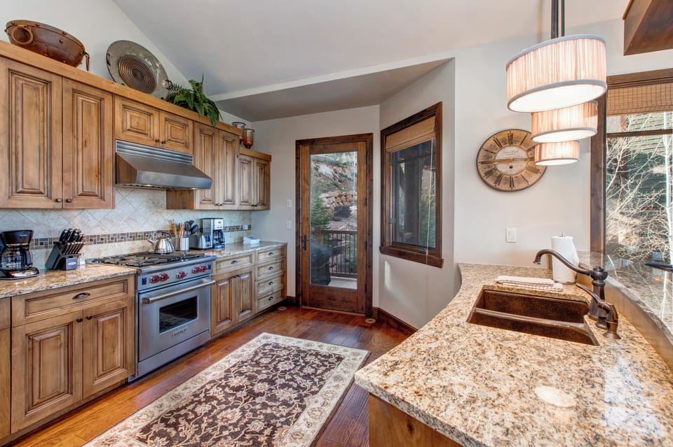 Fully Equipped Kitchen with Stainless steel, high-end appliances, Sub-Zero Fridge, Bar Seating for 3, Granite Countertops, and Private Porch access with BBQ Grill.