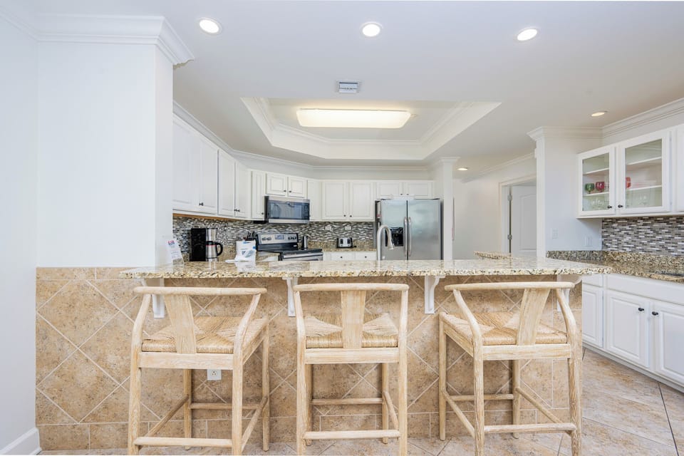 The kitchen features stainless appliances, a granite countertop, and a convenient bar area for casual dining