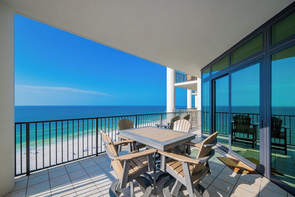 Enjoy stunning beach views from this tenth-floor balcony, featuring comfortable seating and a table for outdoor meals