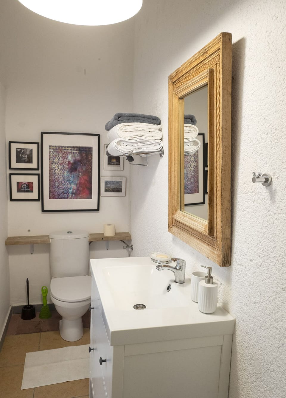 Bath with artworks, antique mirror, modern sink. 