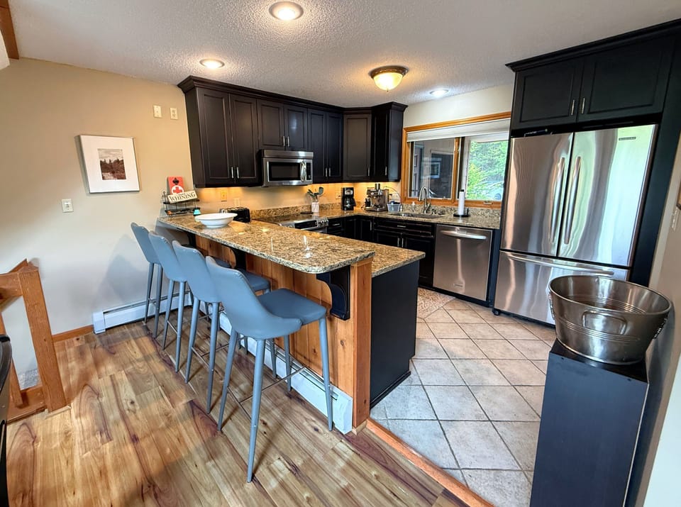 The renovated kitchen features stainless steel appliances, granite countertops, and a spacious breakfast bar with seating for 4 —perfect for preparing meals and gathering with loved ones.