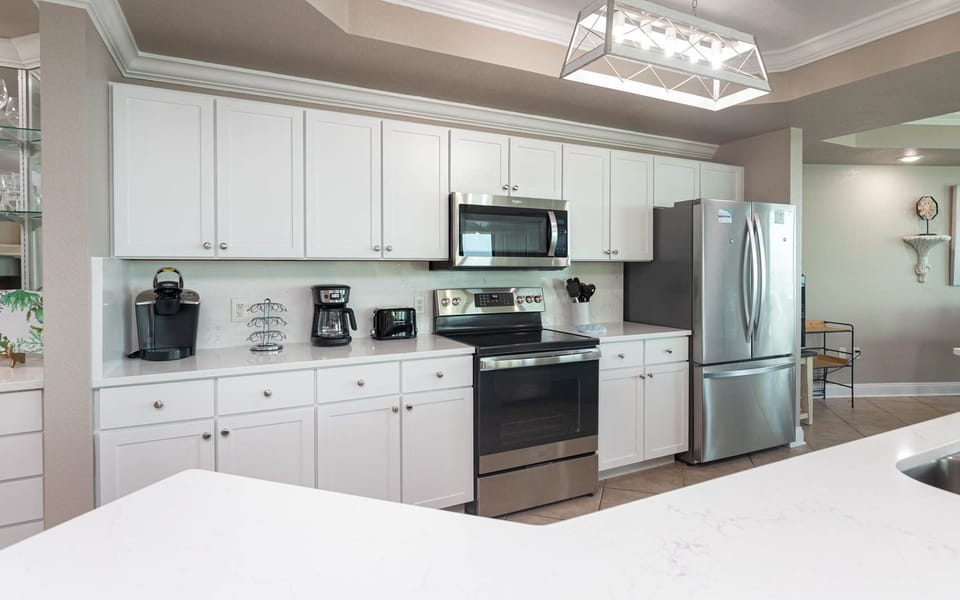 Prepare meals in this kitchen with elegant lighting, stainless appliances, spacious countertops, and coffee corner