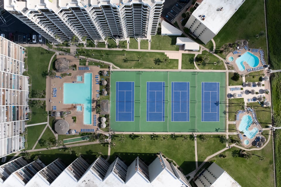An aerial view showcases the property's tennis and pickleball courts along with the surrounding resort amenities.