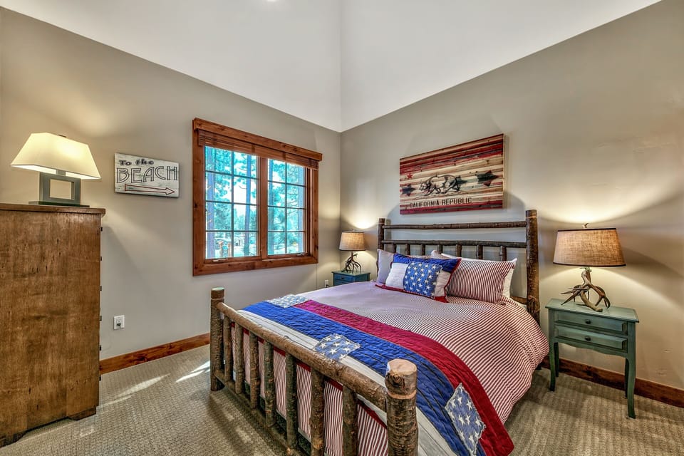 Drift off in your cozy rustic bedroom with patriotic touches and peaceful forest views through charming windows.