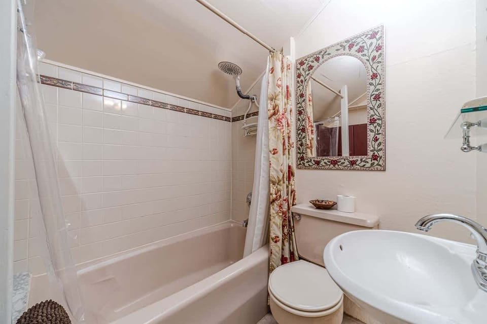 Step into this welcoming bathroom, complete with a comfortable tub, shower, and pedestal sink.