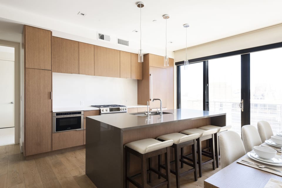 Kitchen island with dune color quartz countertops and seating for 4 in leather and wooden barstools