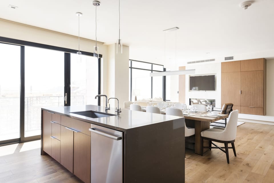 Kitchen island with quartz countertops looking toward the dining room and living room, stunning window walls and sliding glass door to access private patio