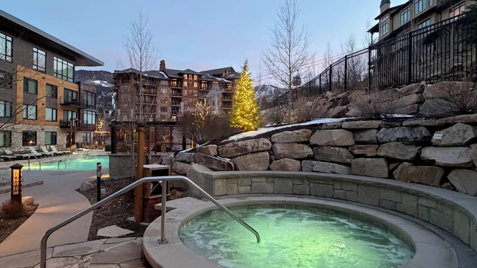 The Lift Condominiums heated hot tub surrounded by natural stone while mountain lights twinkle above.
