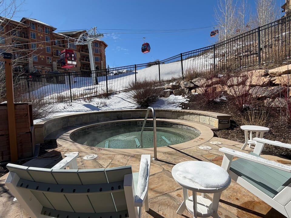 The Lift Condominiums outdoor hot tub with the Sunrise Gondola soaring above snowy slopes..