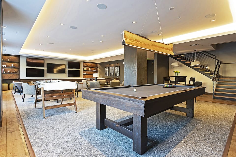 Billiards table in the lift club room with unique wooden linear chandelier