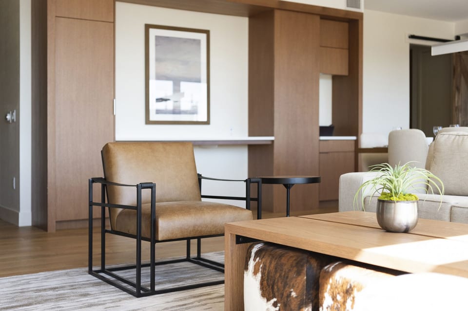 Unique modern mountain design, leather and iron accent chair in the living room, wooden coffee table, and cowhide cube poufs
