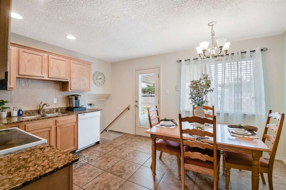Kitchen has a back door with a couple steps out onto a patio and backyard space