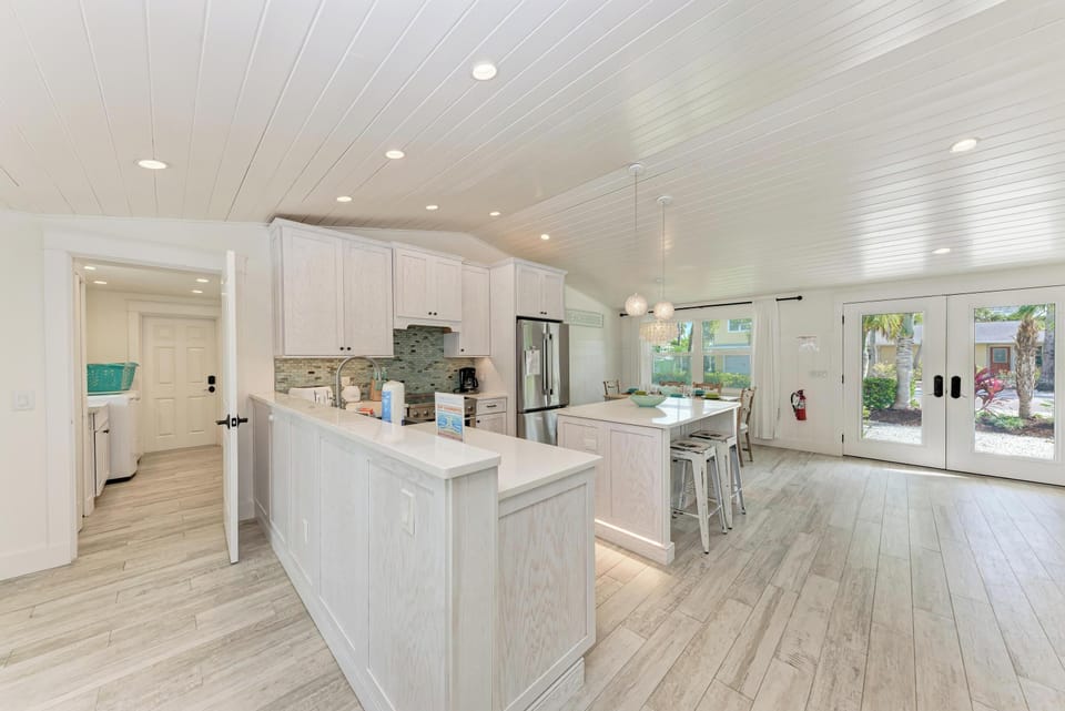 Step into your bright, modern kitchen with pristine white cabinets, spacious island, and stunning ceiling detail—perfect for cooking memories.