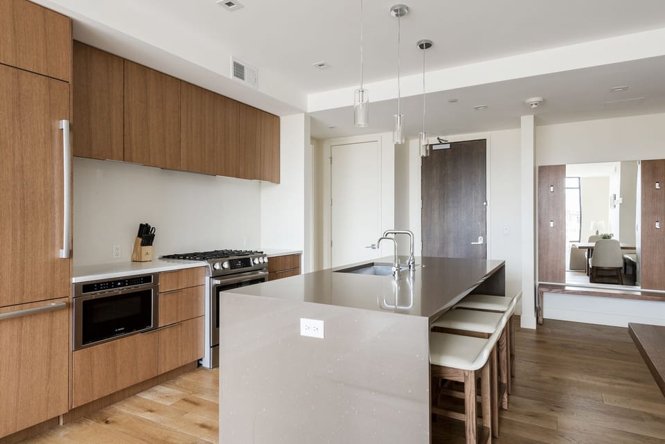 Fully equipped kitchen with dark and white quartz finishes, wood cabinetry and overlay refrigerator