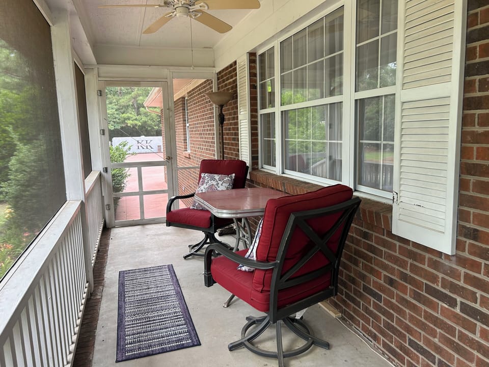 Relax on the screened porch with chairs, table, and views of the front yard.