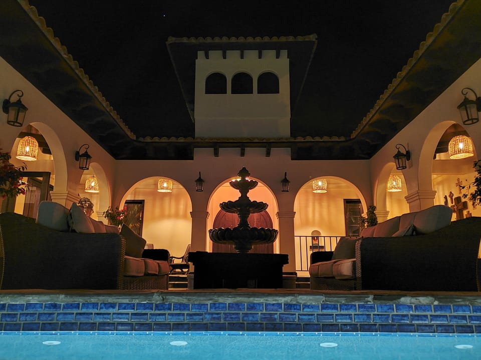 Dramatic lighting, a fountain, and ocean views light up the open courtyard.