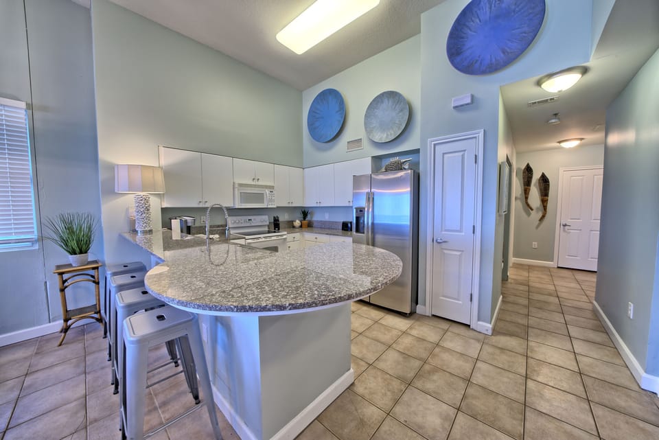 The heart of the condo! ☀️ This open-concept kitchen features soaring ceilings, plenty of seating, and room for everyone to connect after a day at the beach. From pancakes to piña coladas, you've got everything you need.