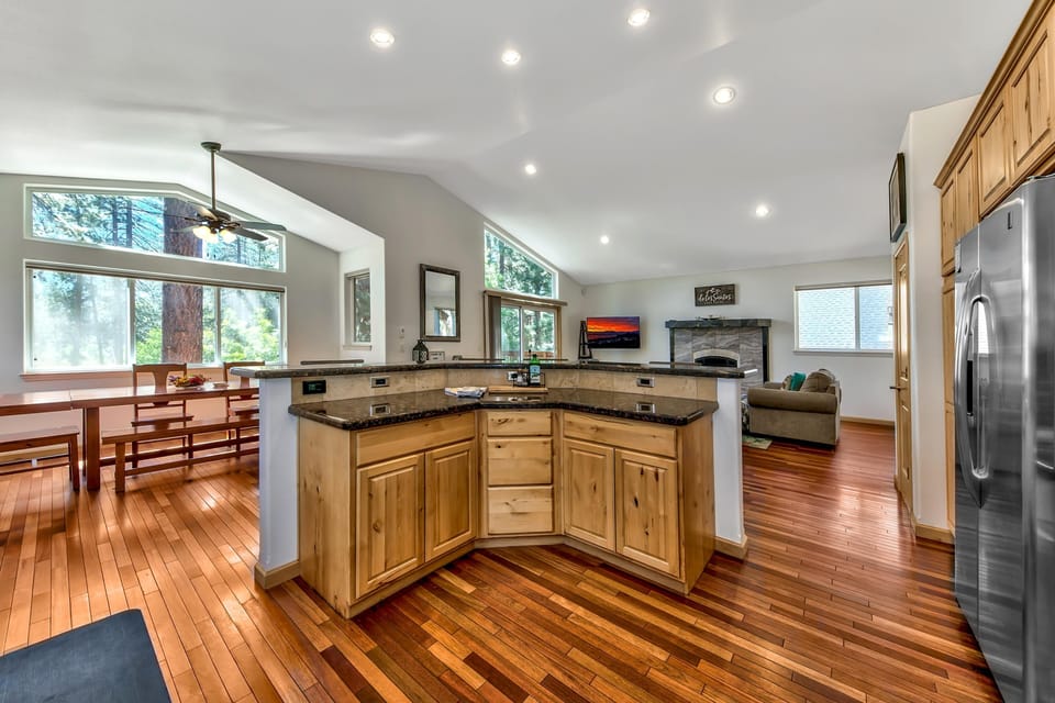 Hardwood floors stretch through the open kitchen with rustic wood cabinets and granite countertops.