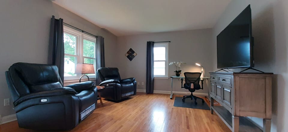 Living room with desk, and smart TV with cable.