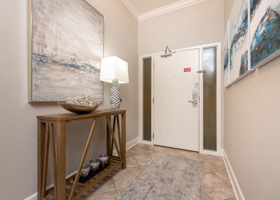 The entryway features a stylish console table, decorative artwork, and a soft rug, setting a warm tone for your stay