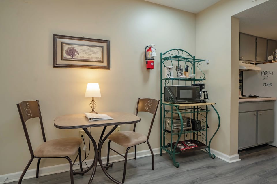 Your cozy dining nook invites you to enjoy morning coffee or a casual meal at the intimate café-style table. A teal shelving unit holds snacks and a microwave for your convenience.