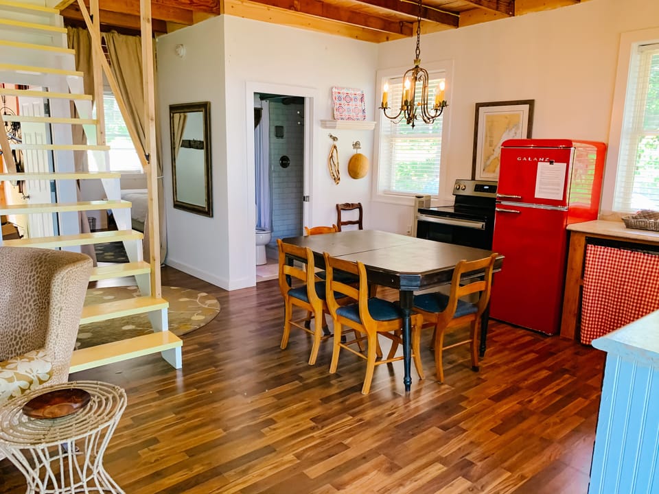 Open floor plan with small sitting area next to eat-in kitchen and loft steps.