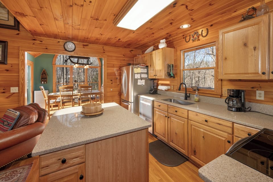 Step into your fully equipped kitchen with warm wood finishes, granite counters, and natural light streaming through skylights above.