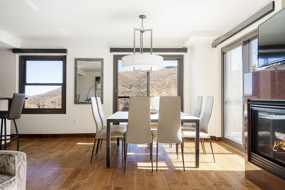 Dining table with seating for 8, round modern chandelier over table, hardwood floors, abundant natural light