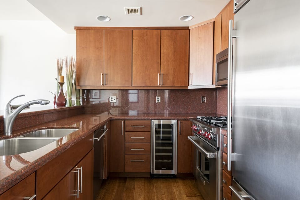 Fully equipped kitchen with stainless steel appliances, red granite countertops, and dark cherry wood cabinets