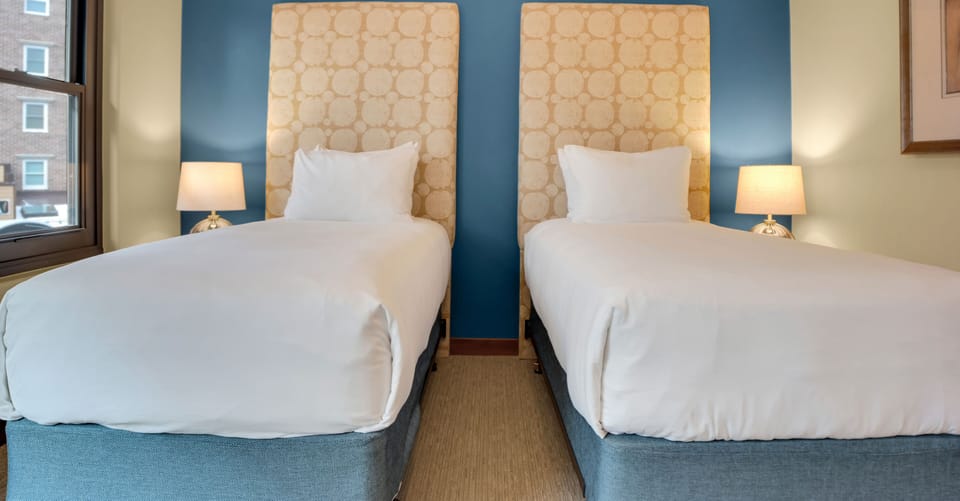Lowell 304's second bedroom with two twin beds that have a large upholstered headboard and blue accent wall.