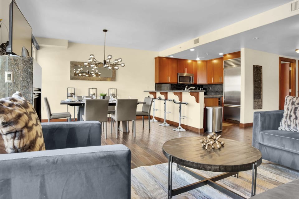 Lowelll 304's open concept living room with grey chair, wood coffee table and next to a spacious dining area and kitchen.