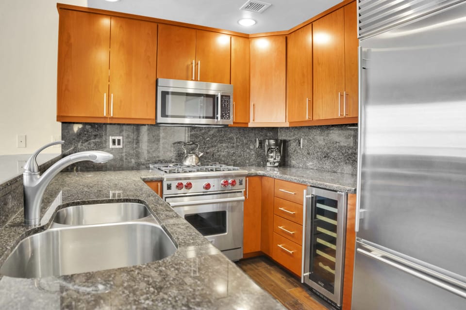 Lowell 304's u-shape kitchen has warm wood cabinets, stainless steel appliances, granite counters, and a wine fridge.