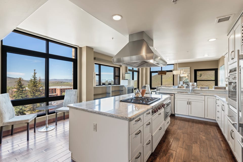 Lowell 401 has a spacious kitchen with white cabinets, center island with a range and hood vent, and granite counter tops.