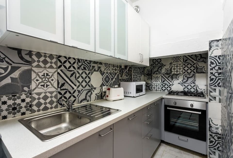 Modern kitchen with a Portuguese tile pattern and cooking appliances.