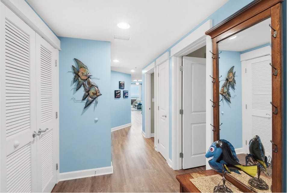 Your beach-themed hallway welcomes you with charming ocean artwork and warm wood floors leading to comfortable coastal bedrooms.