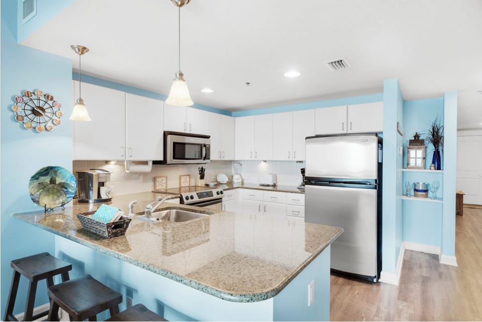 Your fully equipped kitchen features granite counters, stainless appliances, and bright coastal colors that make meal prep a pleasure.