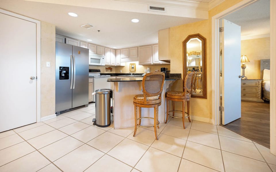 Modern kitchen area features a breakfast bar with seating, granite countertops, and stylish lighting
